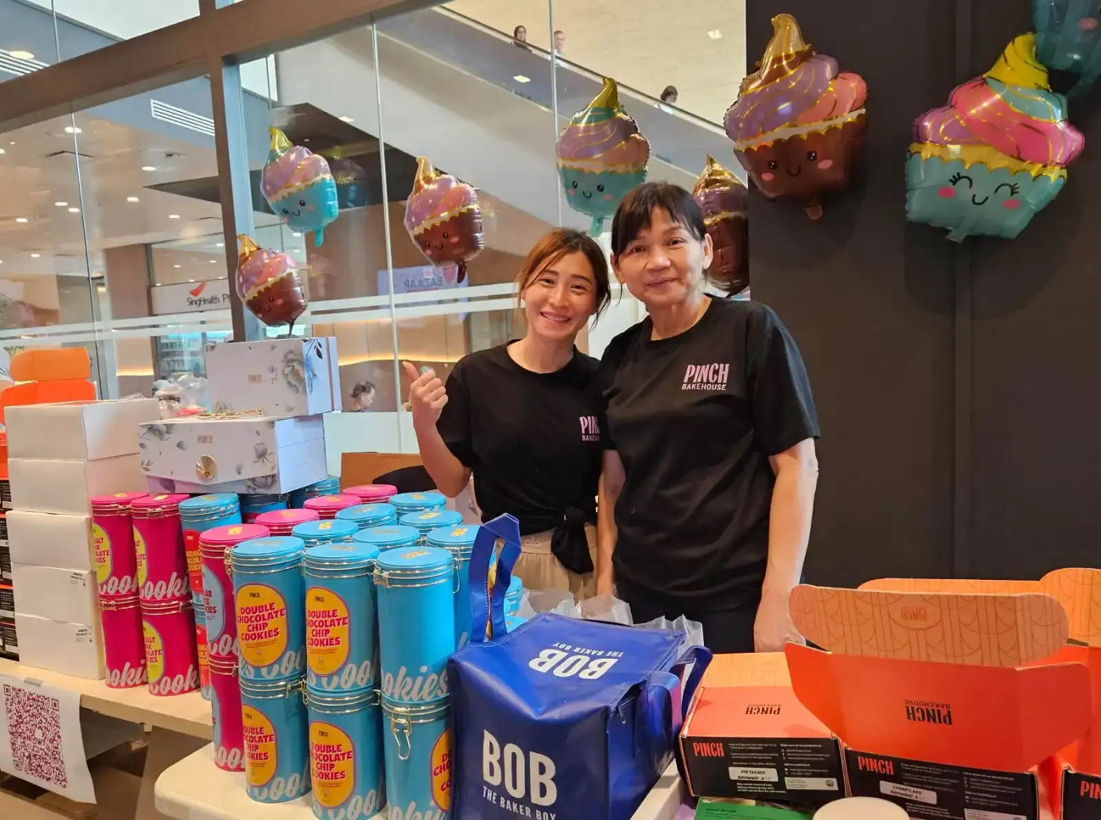 Pinch Bakehouse team at the National Cancer Centre Singapore charity bake sale booth with halal cookies and dessert boxes